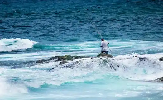 Köpüklü dalgalar arasında surf kamışı hazırlayan balıkçı kıyıdan levrek avına hazırlanıyor.